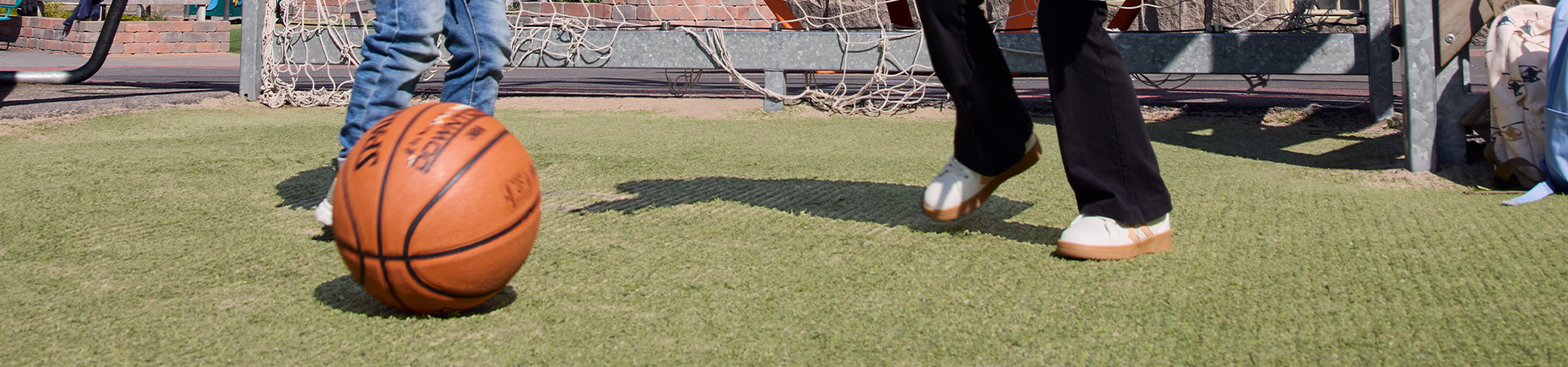 Kinder spielen Fußball auf Rasen vor einem Tor.