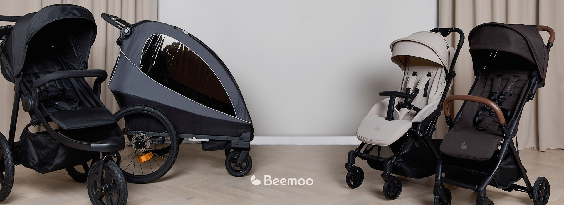 Drei Kinderwagen verschiedener Modelle vor einem Vorhang.