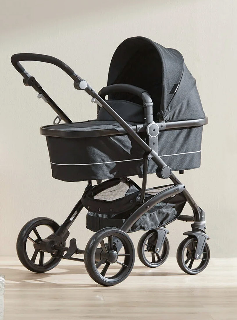 Schwarzer Kinderwagen mit vier Rädern auf Holzboden.