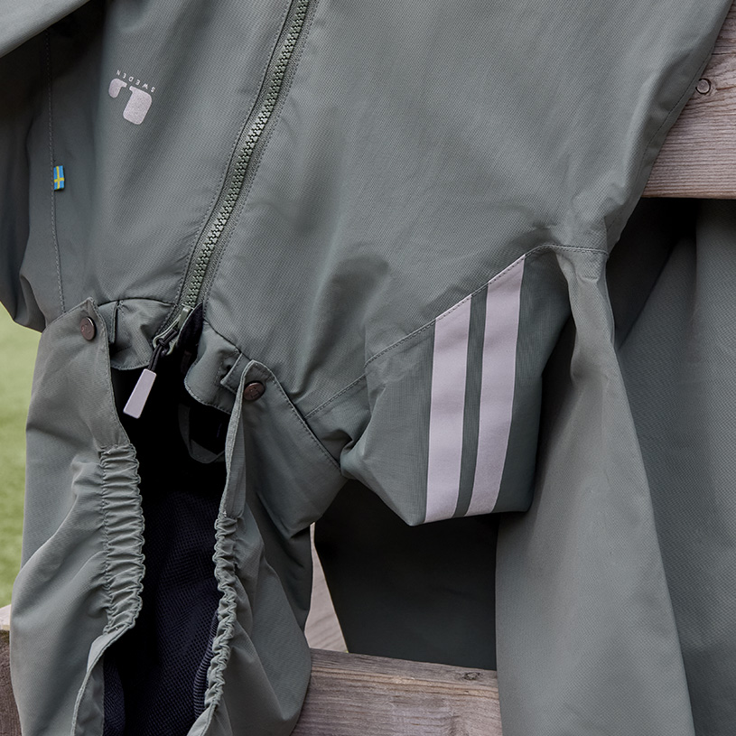 Kind in Winterkleidung und blauer Mütze konzentriert sich auf seine Hände.