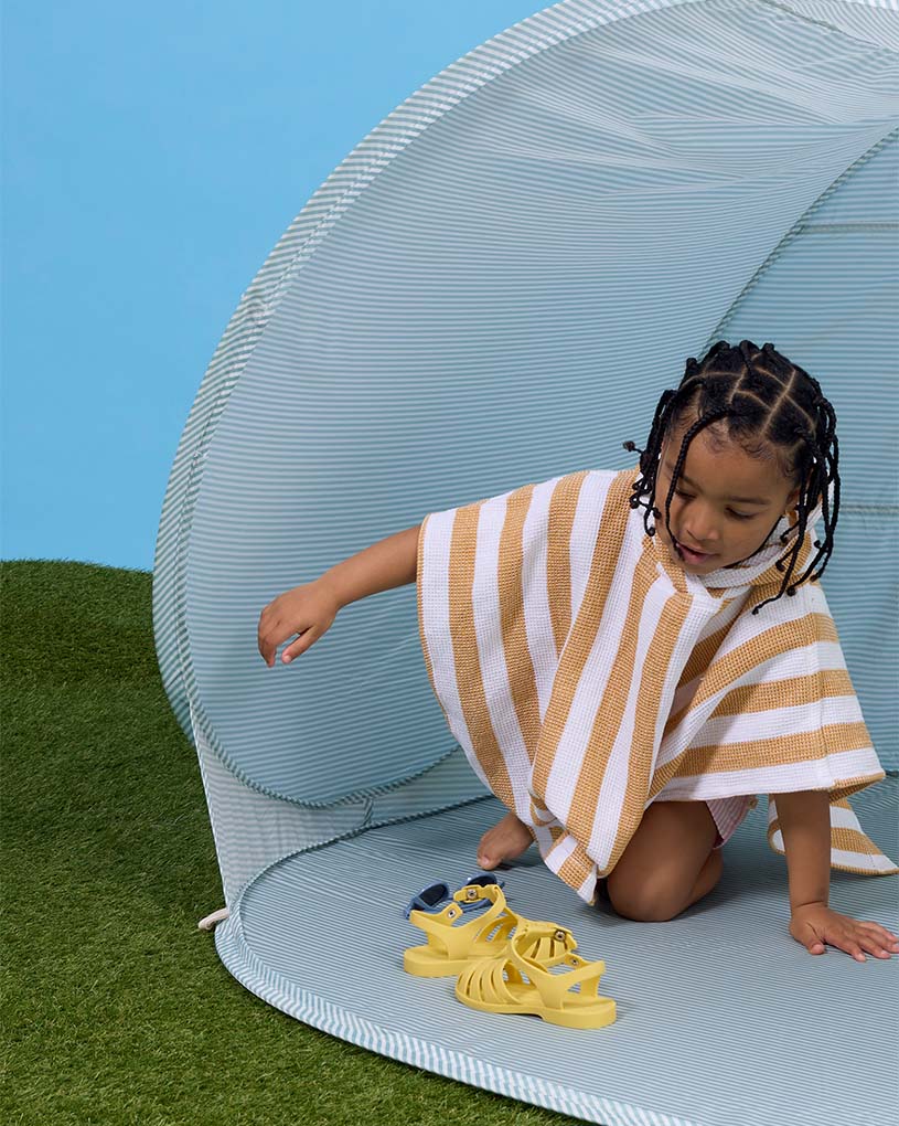 Zwei Kinder spielen in einem Strandzelt am Sandstrand, Text: 'Neuheit!'.