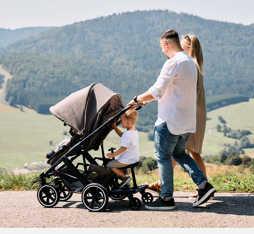 Familie spaziert mit Kinderwagen in idyllischer Umgebung.