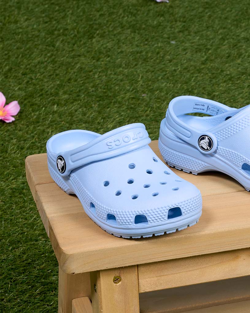 Kind in Sandalen läuft auf Holzterrasse.