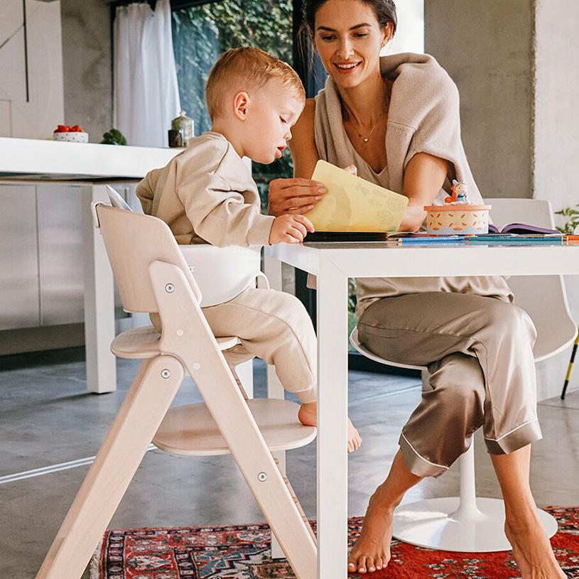 Frau und Kind lesen an einem weißen Tisch in moderner Küche.